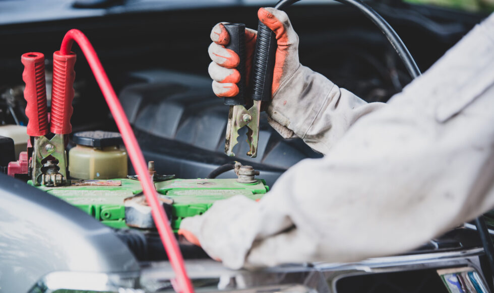 Car repairman wearing a white uniform standing and holding a wrench that is an essential tool for a mechanic